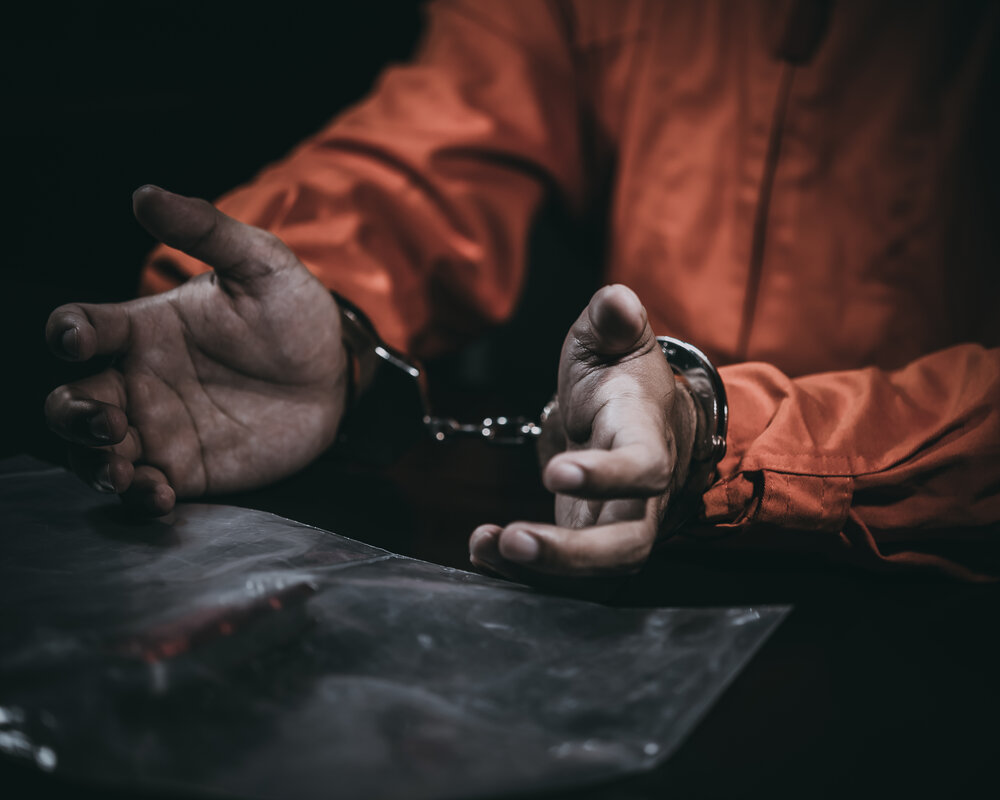 мужчина в наручниках и тюремной робе