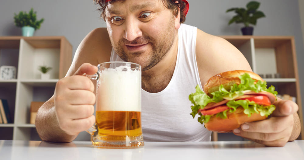Мужчина с пивом и бургером за столом